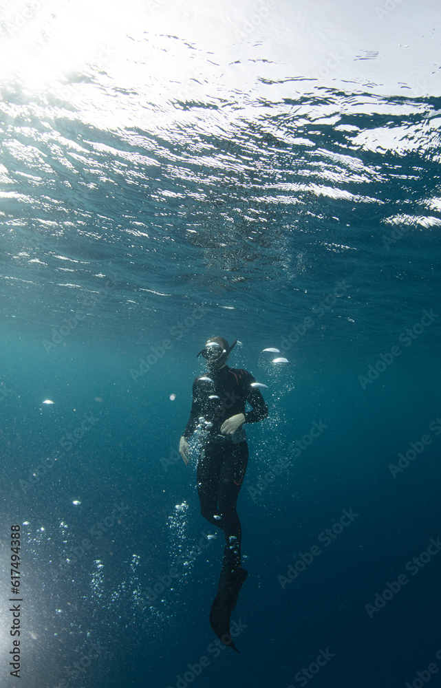 Free diver swimming up on water surface