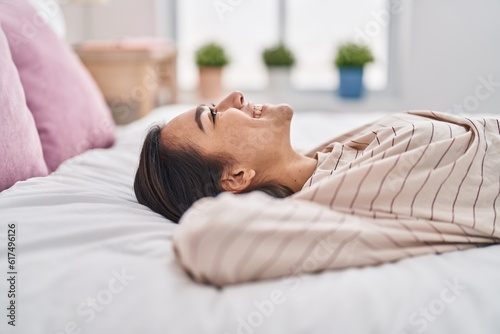 Young hispanic woman smiling confident lying on bed at bedroom