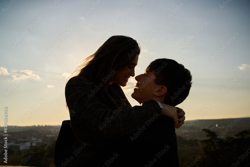 silhouette of a young romantic couple kissing in town