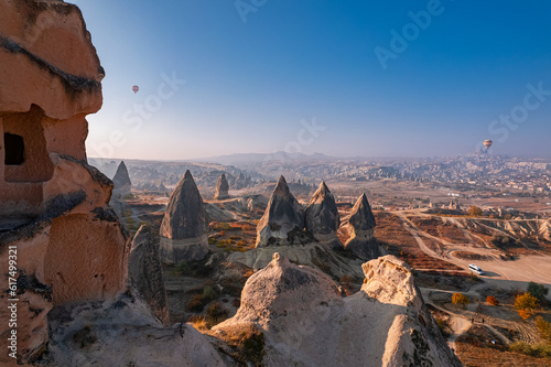 Closeup ancient Goreme cave in big stone, hot air balloons fly over deep canyons, valleys Cappadocia National Park with sunlight, Turkey Travel
