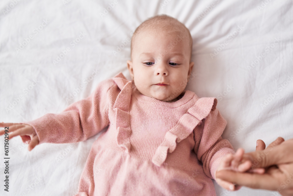 Adorable caucasian baby lying on bed with relaxed expression at bedroom Adorable caucasian baby lying on bed with relaxed expression at bedroom