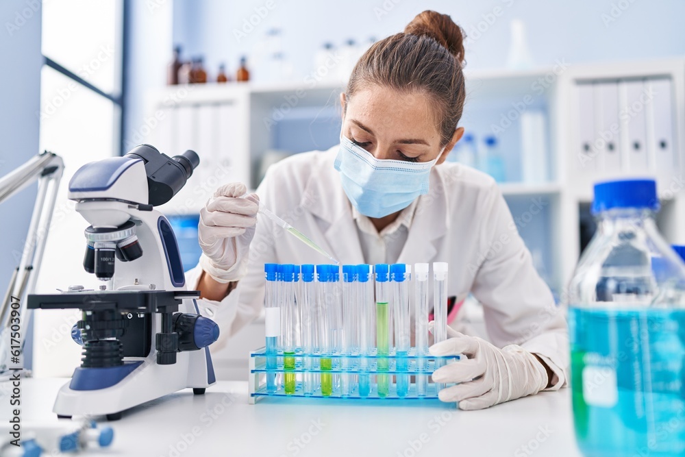 Young woman scientist pouring liquid on test tubes at laboratory Young woman scientist pouring liquid on test tubes at laboratory