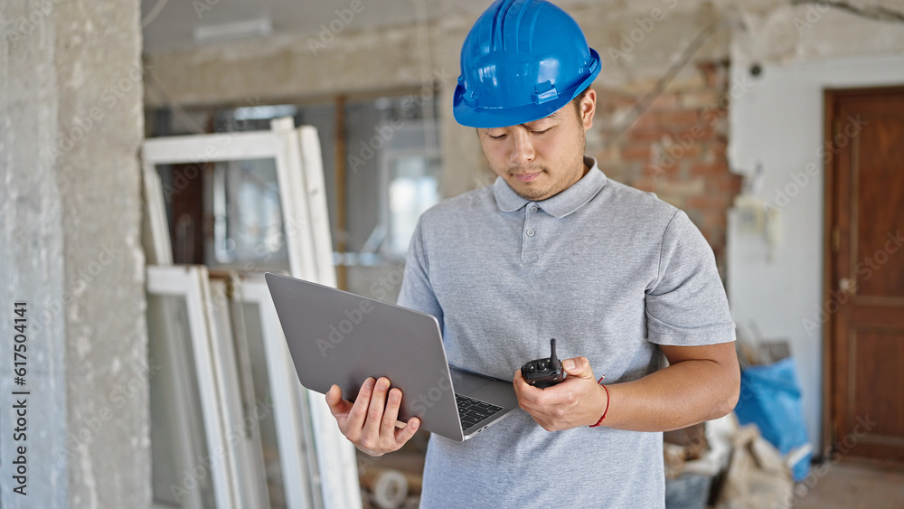 architect using laptop speaking on walkie talkie at construction site architect using laptop speaking on walkie talkie at construction site
