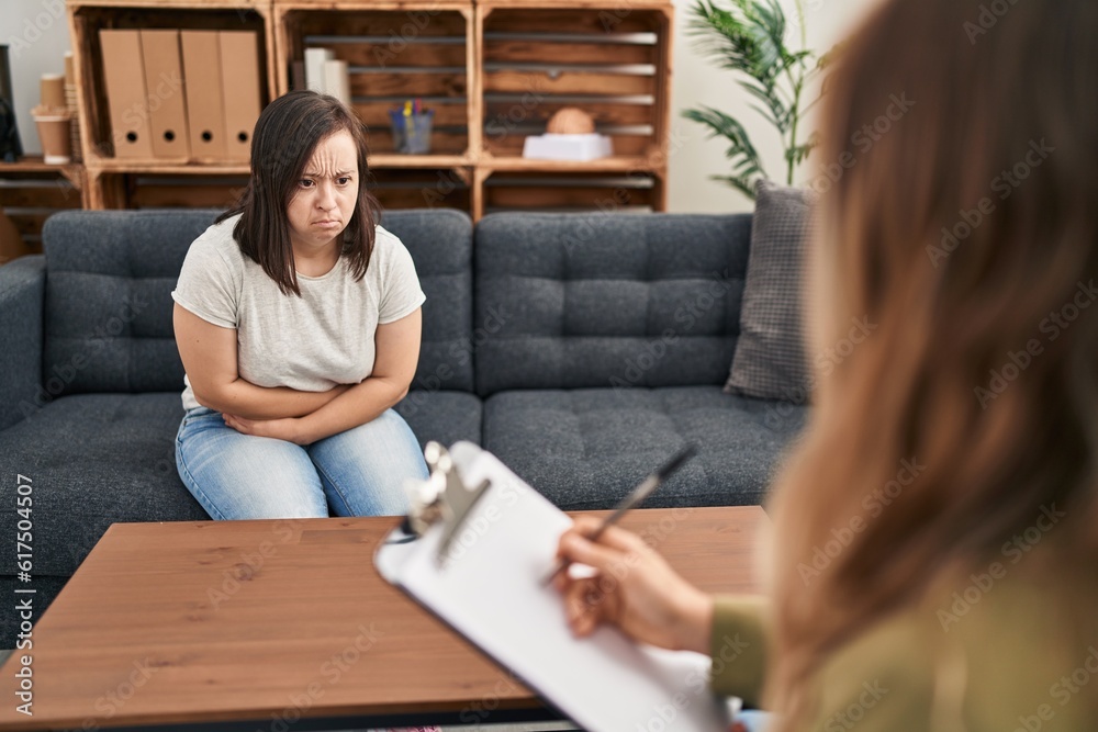 Hispanic girl with down syndrome doing therapy with hand on stomach because indigestion, painful illness feeling unwell. ache concept. Hispanic girl with down syndrome doing therapy with hand on stomach because indigestion, painful illness feeling unwell. ache concept.