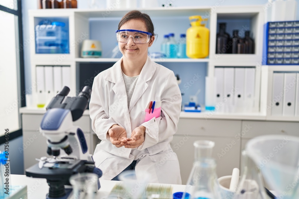 Hispanic girl with down syndrome working at scientist laboratory with hands together and crossed fingers smiling relaxed and cheerful. success and optimistic Hispanic girl with down syndrome working at scientist laboratory with hands together and crossed fingers smiling relaxed and cheerful. success and optimistic