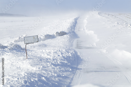 A rural mailbox by a country road which is closing with blowing drifting snow in Pennsylvania, USA.