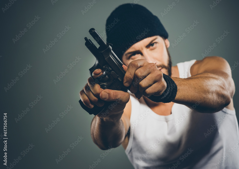 Handsome aggressive criminal with cap holding a gun Handsome aggressive criminal with cap holding a gun