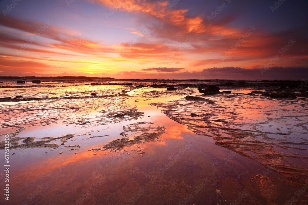 Sunrise skies reflecting on the exposed rock shelf at Long Reef, Northern Beaches, Australia