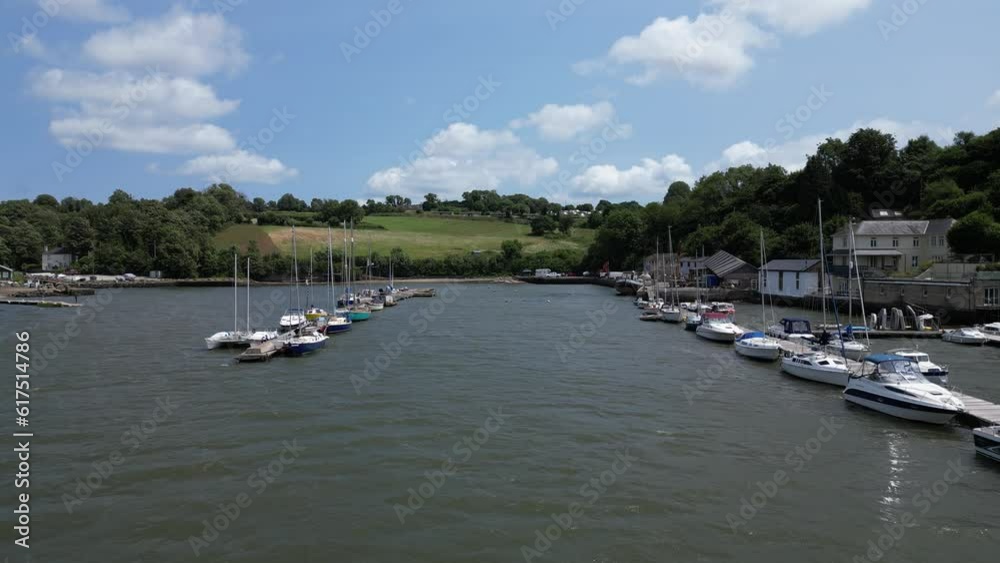 Galmpton Creek, South Devon, England: DRONE AERIAL VIEWS: The drone flies low over the water between two columns of boats and yachts moored at Galmpton Creek jetties. Galmpton Creek, South Devon, England: DRONE AERIAL VIEWS: The drone flies low over the water between two columns of boats and yachts moored at Galmpton Creek jetties.