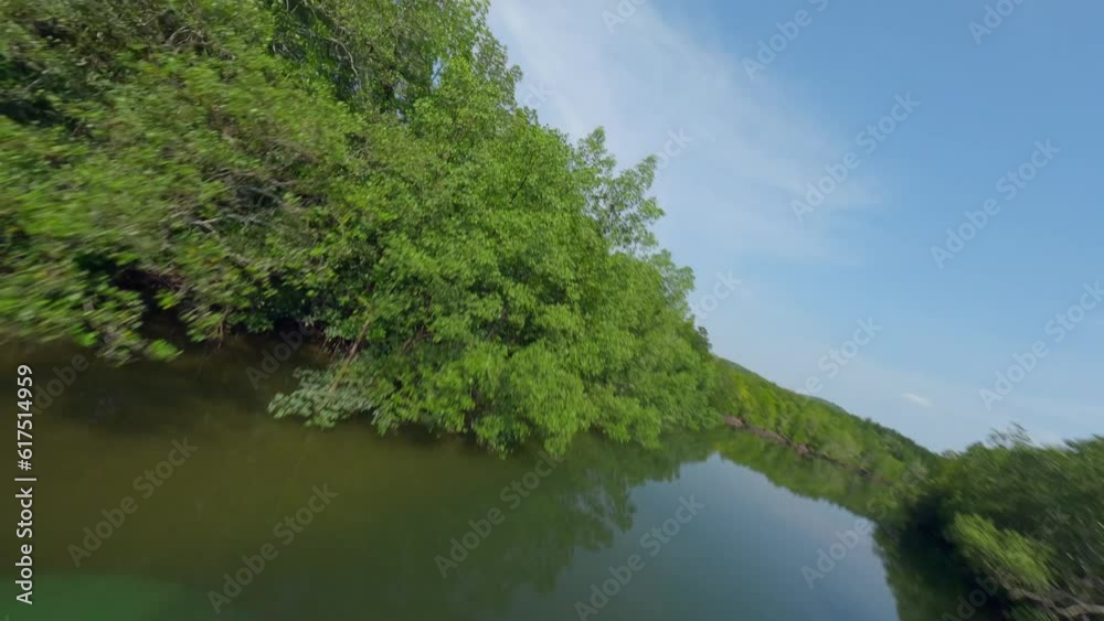 Aerial view freestyle dynamic flying over calm river surface green trees forest with village harbor port Asian fishing boat. FPV sport drone shot tropical pond embankment rustic house nature lush 4k Aerial view freestyle dynamic flying over calm river surface green trees forest with village harbor port Asian fishing boat. FPV sport drone shot tropical pond embankment rustic house nature lush 4k
