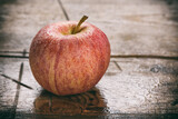 wet fresh red apple on rustic wooden table