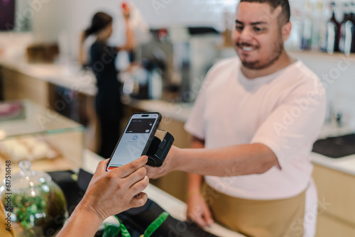 atendente recebendo pagamento por aproximação com o celular em umacafeteria no Brasil photo