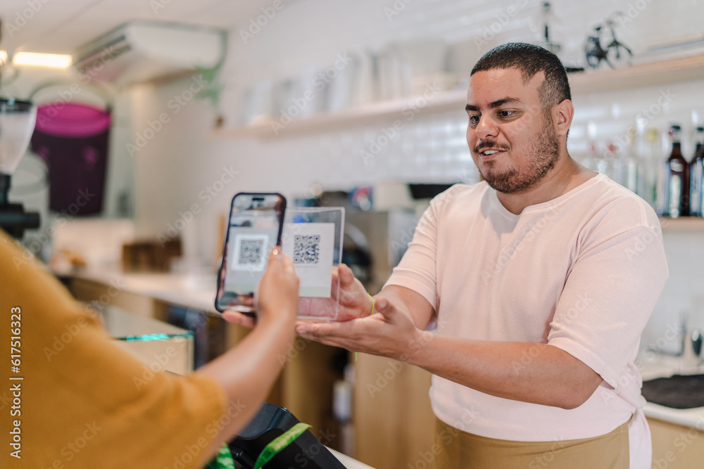 atendente recebendo o pagamento da conta por leitura de código QR em uma cafeteria no Brasil