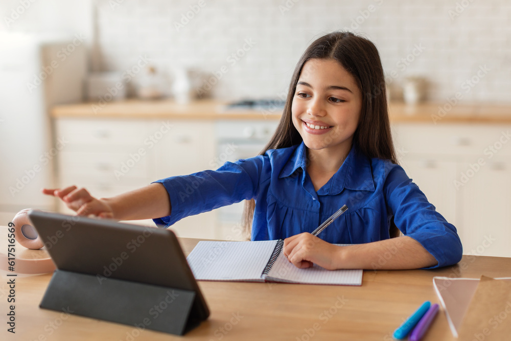 Girl using digital tablet doing homework in modern home interior Girl using digital tablet doing homework in modern home interior