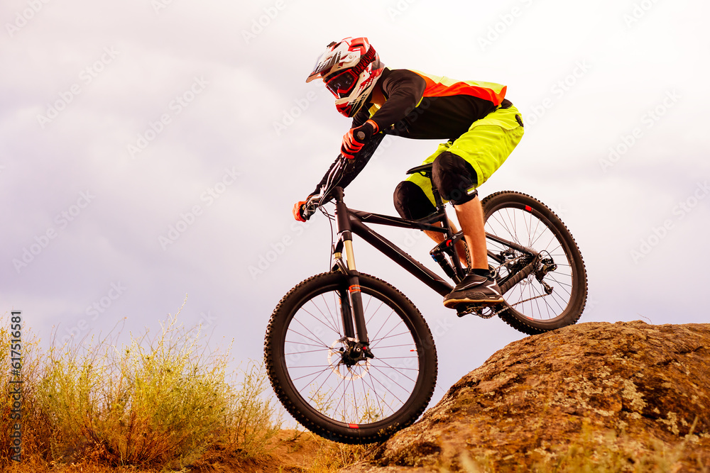 Professional Cyclist Riding the Bike Down Rocky Hill. Extreme Sport Concept. Free Space for Text. Professional Cyclist Riding the Bike Down Rocky Hill. Extreme Sport Concept. Free Space for Text.