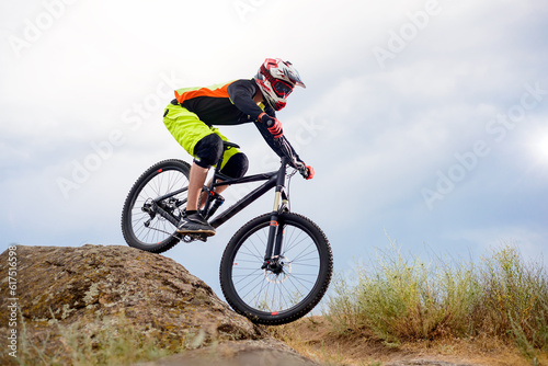 Professional Cyclist Riding the Bike Down Rocky Hill. Extreme Sport Concept. Free Space for Text.