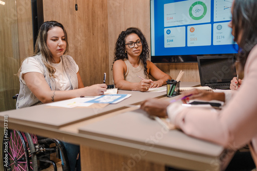 Foto empresária Brasileira com deficiência física em reunião com colegas de trabalho