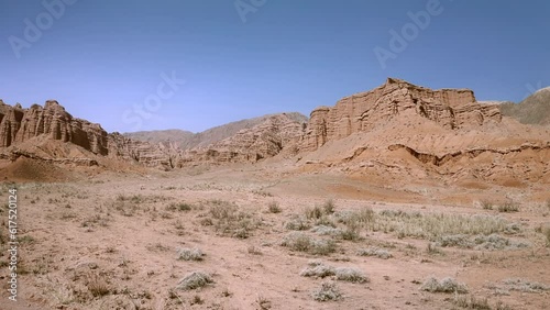Slow low flight over a desert rocky terrain covered with red sand with table mountains. Desert landscape shot from above in 4K