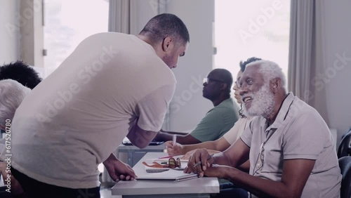 professor Brasileiro na mesa de um aluno idoso explicando a licao de matematica em um curso para adultos e idosos no Brasil photo