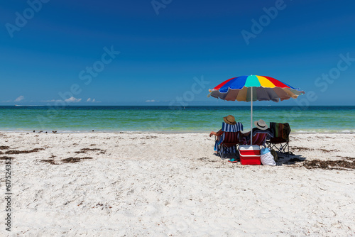 Beautiful sandy beach with colorful umbrella and beach chairs in tropical beach park in Naples, Florida © lucky-photo