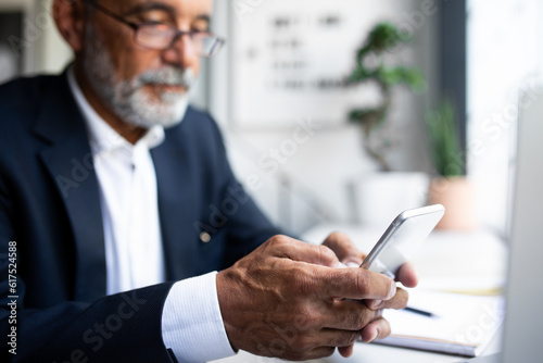 Serious mature european man in suit chatting on phone, use app for check account in office interior, cropped