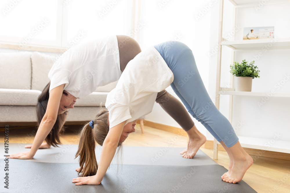 Serious millennial caucasian woman in sportswear and teen daughter practice yoga, doing handstand