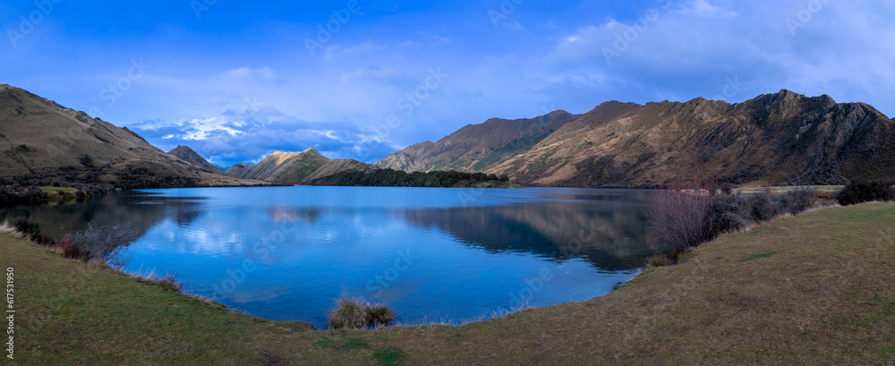 Photograph of Lake Moke with mountains reflecting in the water on a cloudy day outside Queenstown on the South Island of New Zealand