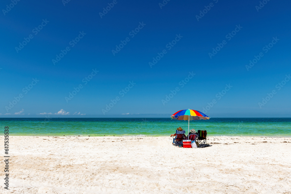 Sunny beach with colorful umbrella and beach chairs in tropical beach