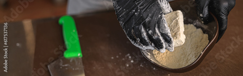 The chef breads the cheese in flour before frying it in a pan in restaurant kitchen