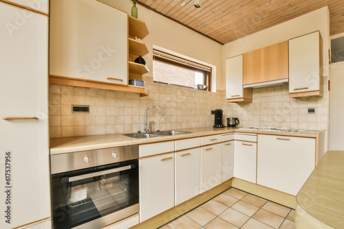 a small kitchen with white cabinets and wood paneled ceiling above the sink is an oven, dishwasher and microwave