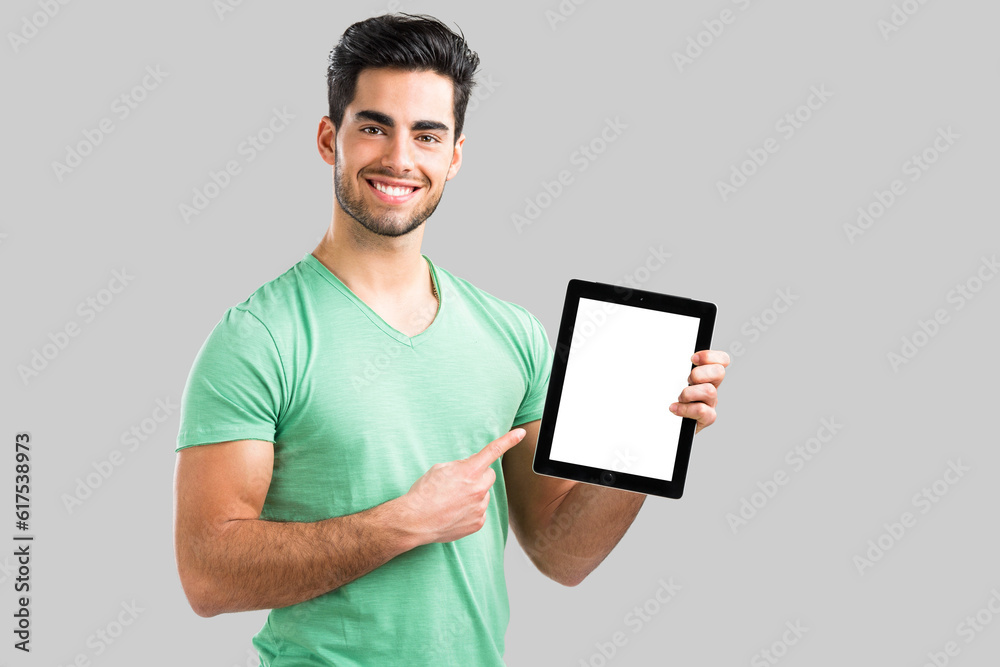 Handsome young man showing something on a tablet, isolated over gray background Handsome young man showing something on a tablet, isolated over gray background