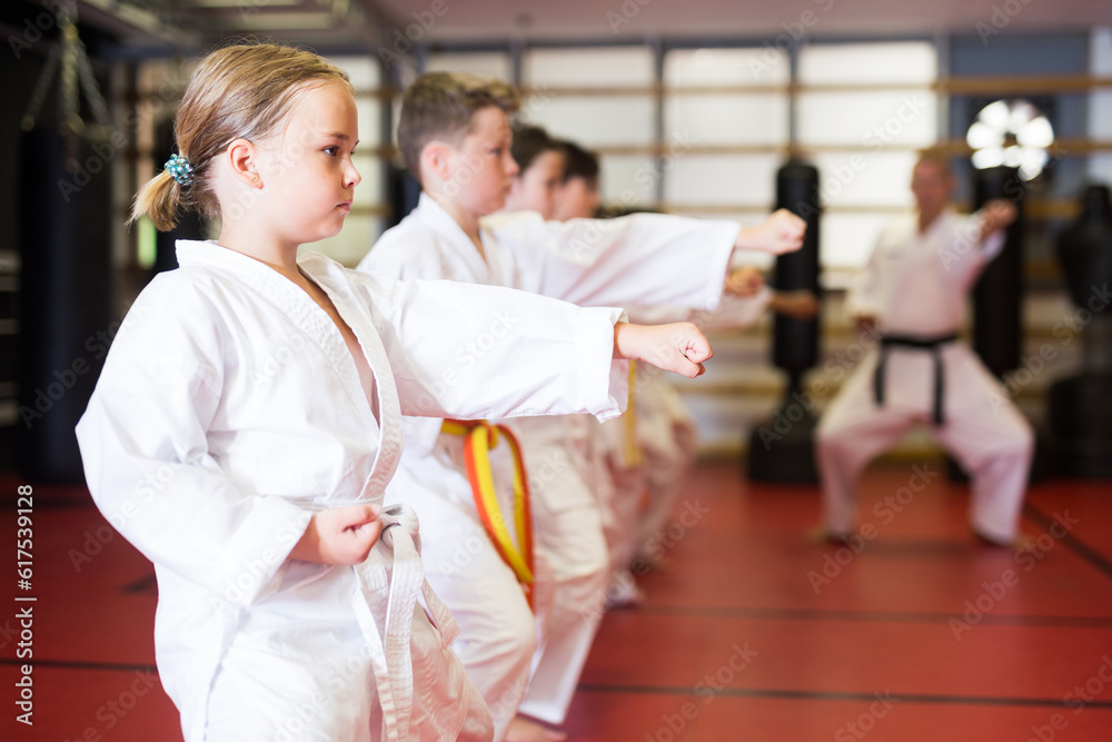 Preteen girl wearing in kimono attempting to master new moves in sport gym