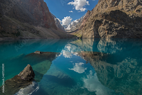 Blue lake surrounded with rocks. Blue sky and clouds reflects in water. Big Alo is the most beauty lake of Fann Mountains