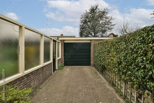 a house in the netherlands, with a green garage door and brick driveway leading up to the home's entrance