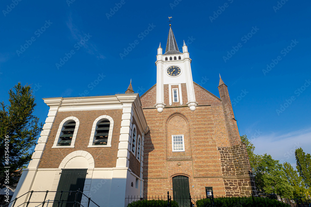 White clock tower of Reformed Church (Dutch: Gereformeerde or Hervormde kerk) The oldest building in the town centre, Bouwstraat, Ommen, A city in the Dutch province of Overijssel, Netherlands.