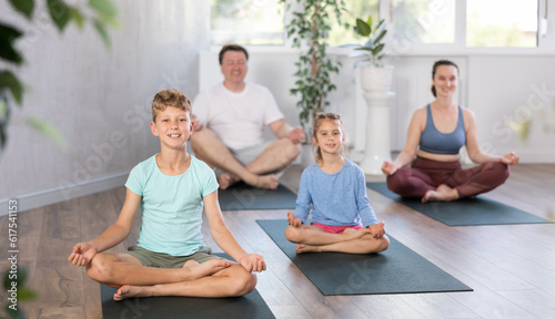 Teenage girl with her parents practices yoga in the lotus position