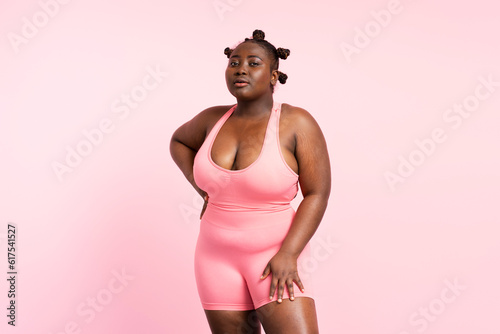 Attractive african american sportswoman wearing fitness uniform, bra isolated on pink background