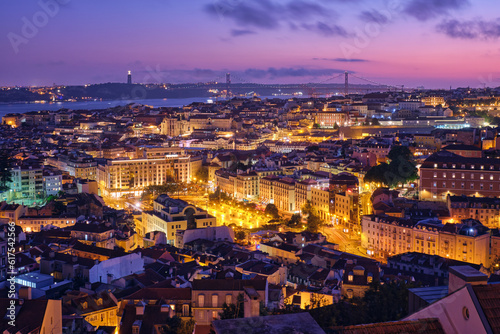 Night view of Lisbon famous view from Miradouro da Senhora do Monte tourist viewpoint of Alfama and Mauraria old city districts  25th of April Bridge in the evening twilight. Lisbon  Portugal