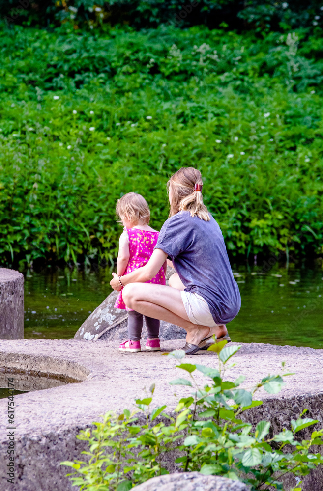 Fototapeta premium A woman and her daughter are standing on the lake in summer 