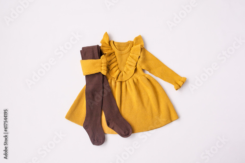 Yellow dress and brown leggings. Look for a girl. Children's wardrobe. Layout, white background, top view. High quality photo