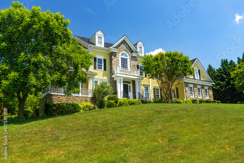 Big luxury house with nicely landscaped front yard and mowed lawn in the suburbs. Summer day, blue sky. © kosoff