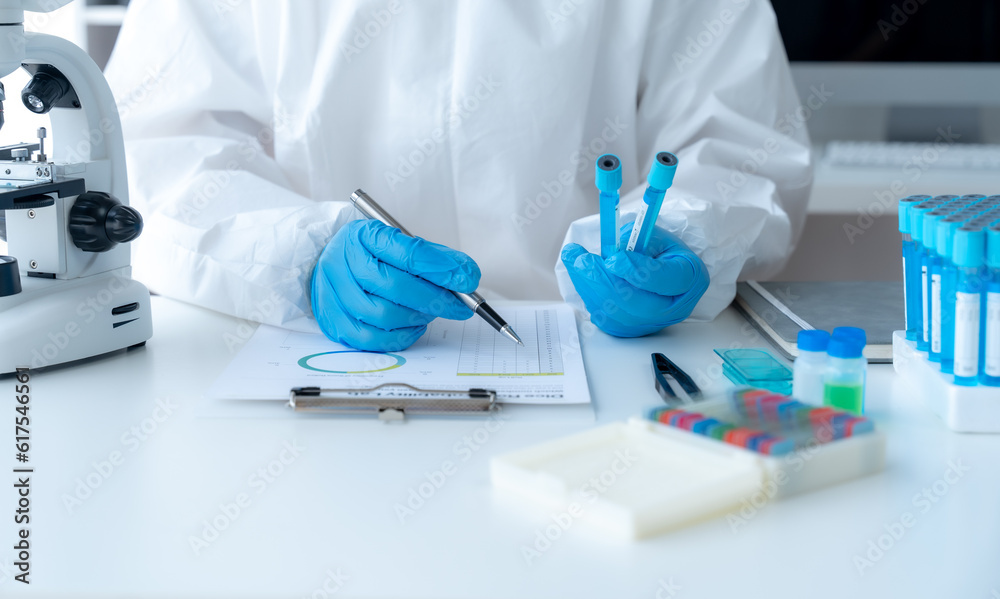Doctor hand taking a blood sample tube from a rack with machines of analysis in the lab background, Technician holding blood tube test in the research laboratory. Doctor hand taking a blood sample tube from a rack with machines of analysis in the lab background, Technician holding blood tube test in the research laboratory.