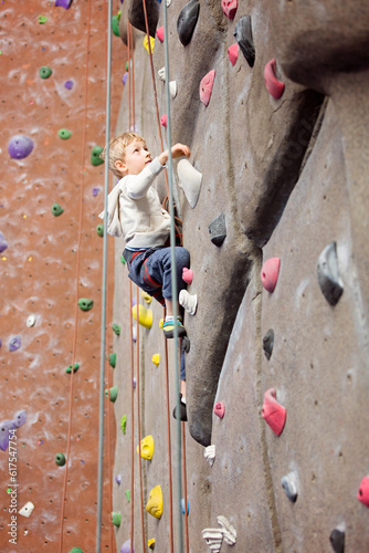 brave little boy rock climbing at indoor climbing gym, healthy and active lifestyle