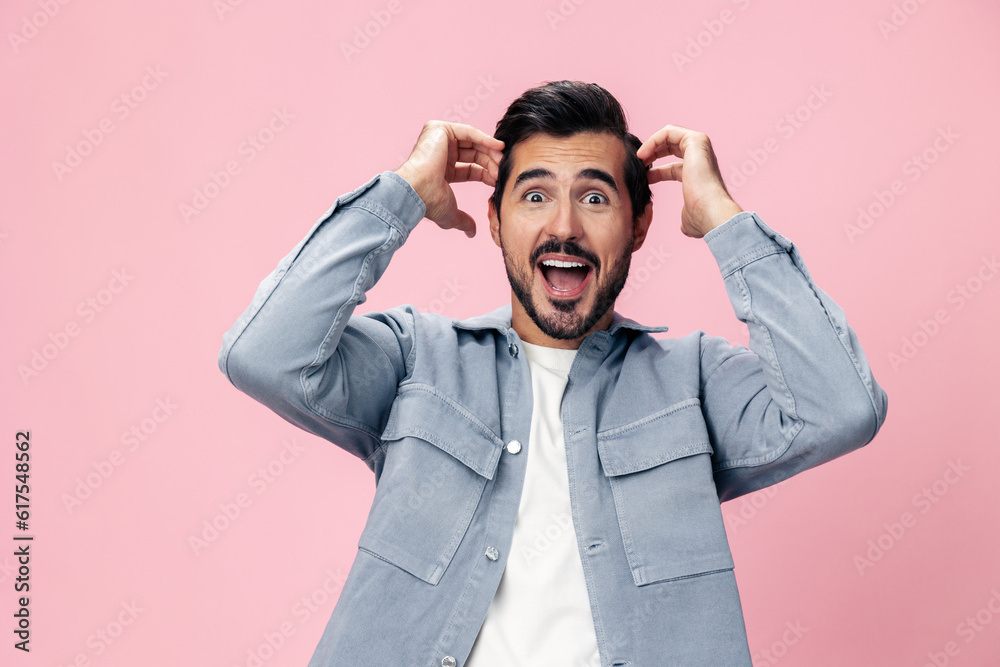 Portrait of a stylish brunette man with a beard raised his hands up with surprise open pink background in a white T-shirt and jeans smile and joyful emotion on his face, copy space