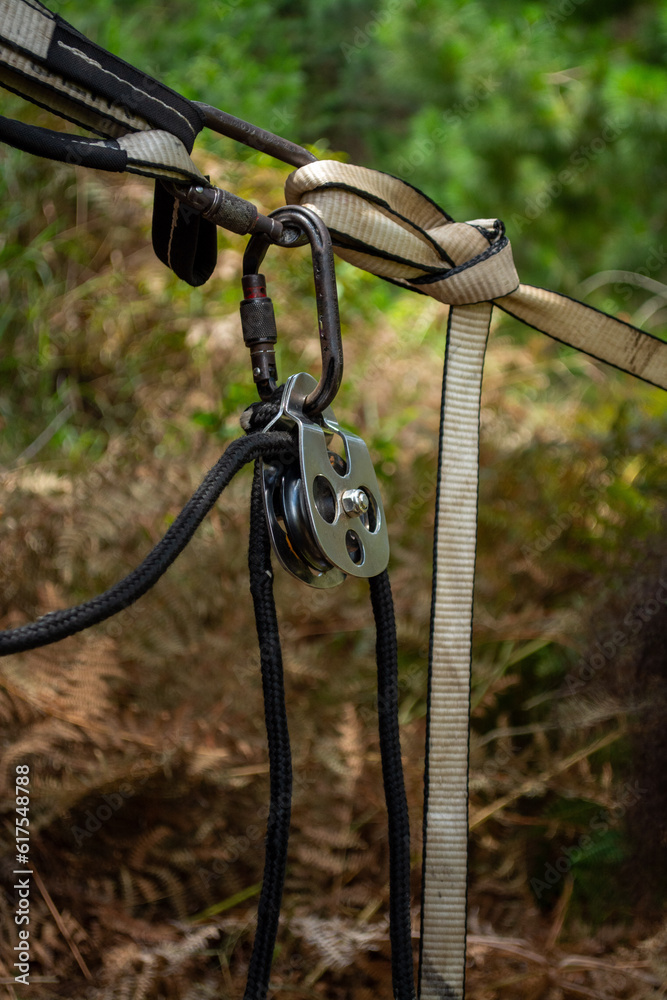 Obraz premium Vertical picture Details of Highline pulley, carabiner and ropes equipment with nature behind