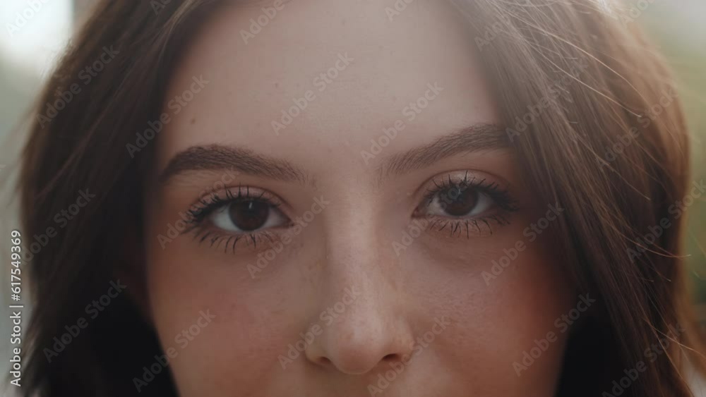 Portrait of an attractive young woman with expressive eyes close up who standing outdoors in a backlight and looking at the camera. Concept of urban carefree summer life Portrait of an attractive young woman with expressive eyes close up who standing outdoors in a backlight and looking at the camera. Concept of urban carefree summer life