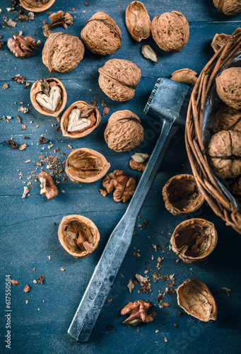 Walnut in wicker basket on blue old wooden board rustic style with nutshell top view.
