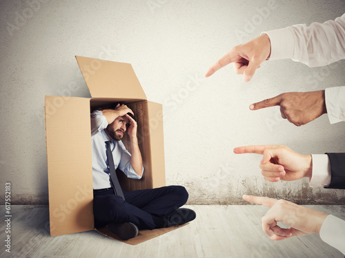 Businessman indicated by colleagues hiding in a cardboard