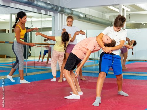 Young children working in pair mastering new self-defense moves at gym during group class