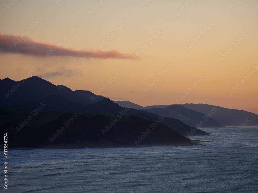 Colorful pastel sky sunrise view of mountain silhouette layered seaside hills at Castle Point, Wellington New Zealand